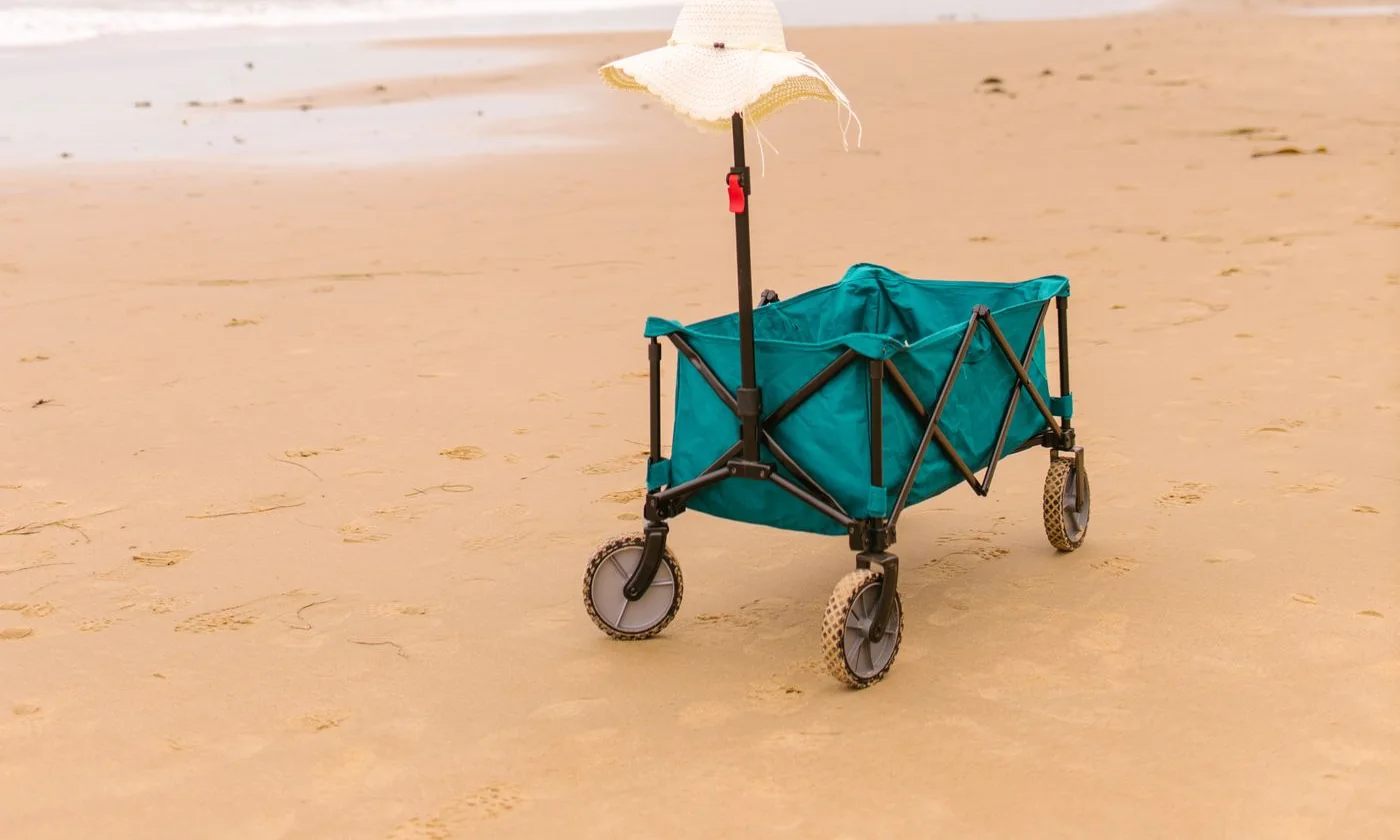Blue beach cart carrying a sunhat on a sandy shore