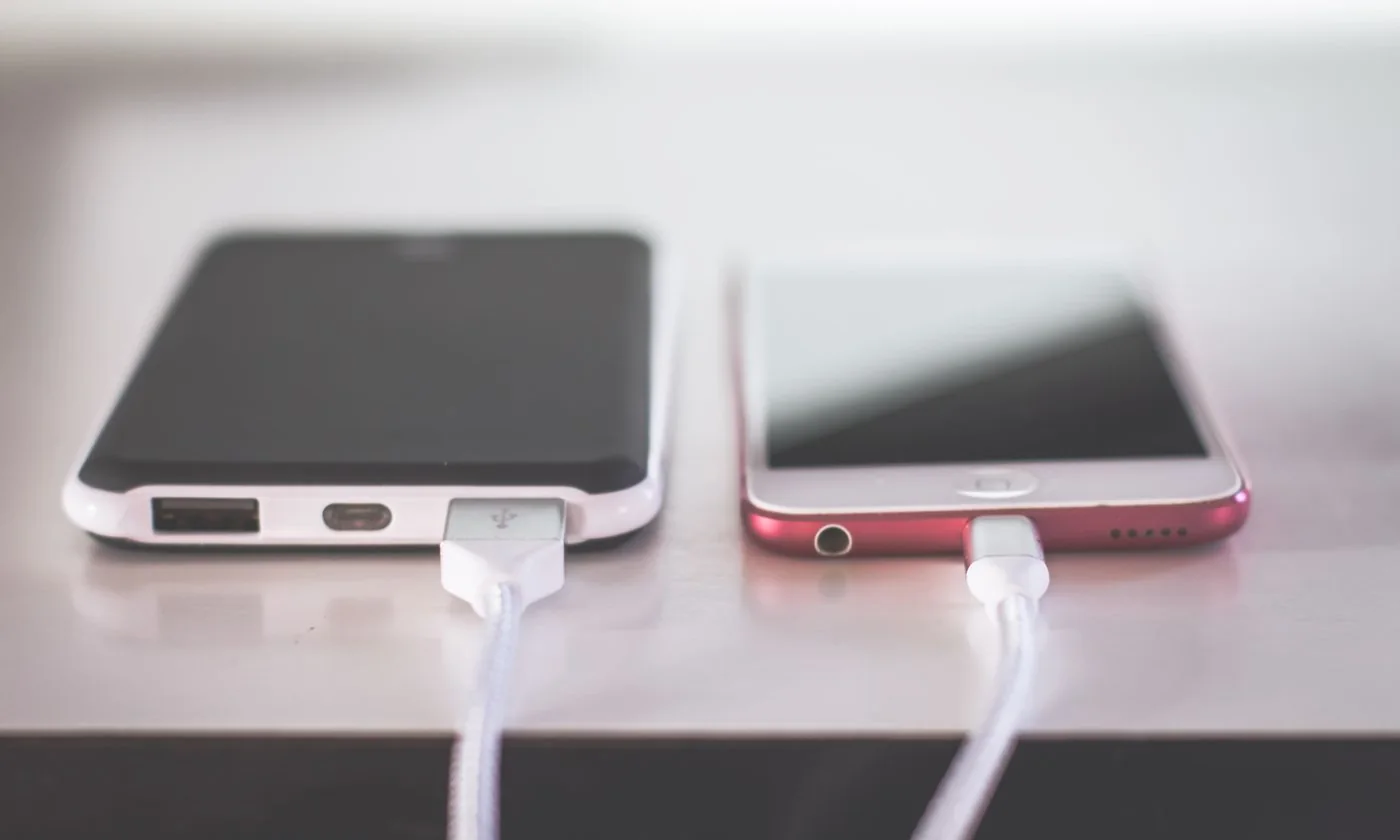 Two smartphones connected to charging cables on a desk